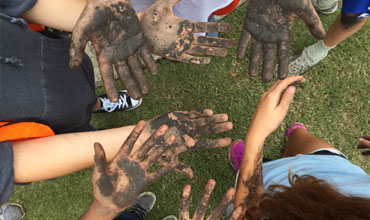 Hands covered in soil from a gardening activity at The Exploris School, showing students’ participation in outdoor learning.